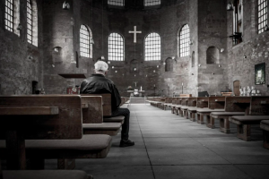 older man sits alone in the pews of a church